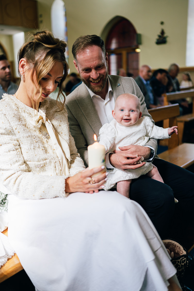Smiling baby boy in white christening gown during ceremony in Sligo
