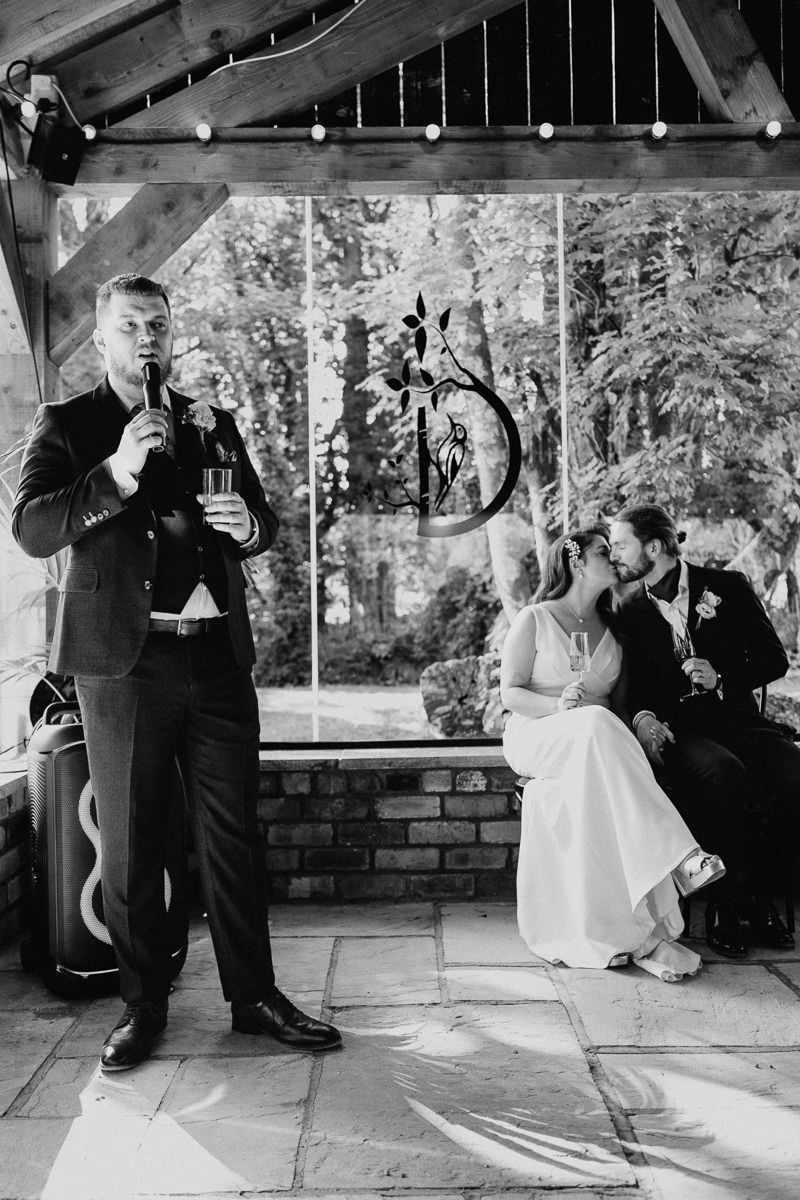 Wedding speech with the bride and groom kissing in the background at Drumhierny Woodland Hideaway, Sligo